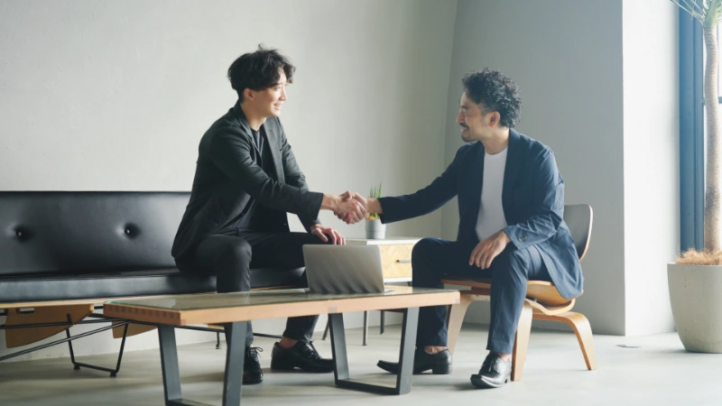 座って握手をする人々のイメージ